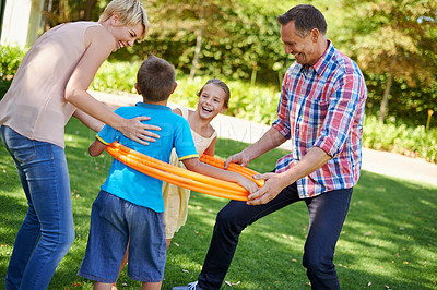 Buy stock photo Parents, children and hula hoop in park as family, playing and bonding with motor skills outdoor. Kids, son and daughter with mother and father in nature for leisure, childhood development with smile