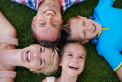 Buy stock photo A cropped high angle shot of a happy family lying on the grass with their heads together