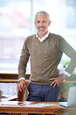 Buy stock photo A portrait of a mature businessman standing at his desk in his office