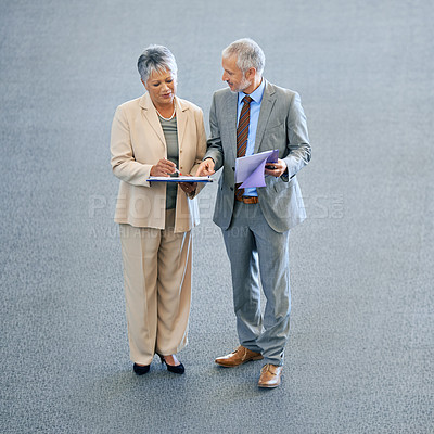 Buy stock photo Shot of a businesswoman and her male colleague discussing documents