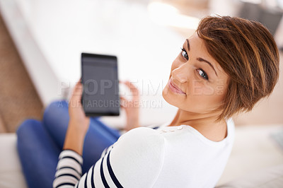Buy stock photo Shot of a beautiful young woman reading her tablet while relaxing at home