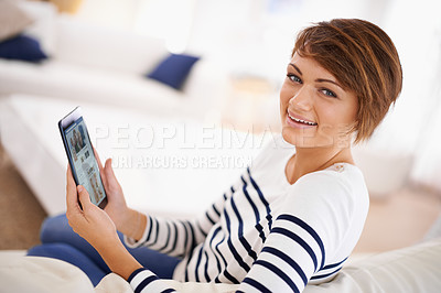 Buy stock photo Shot of an attractive young woman relaxing at home with her tablet
