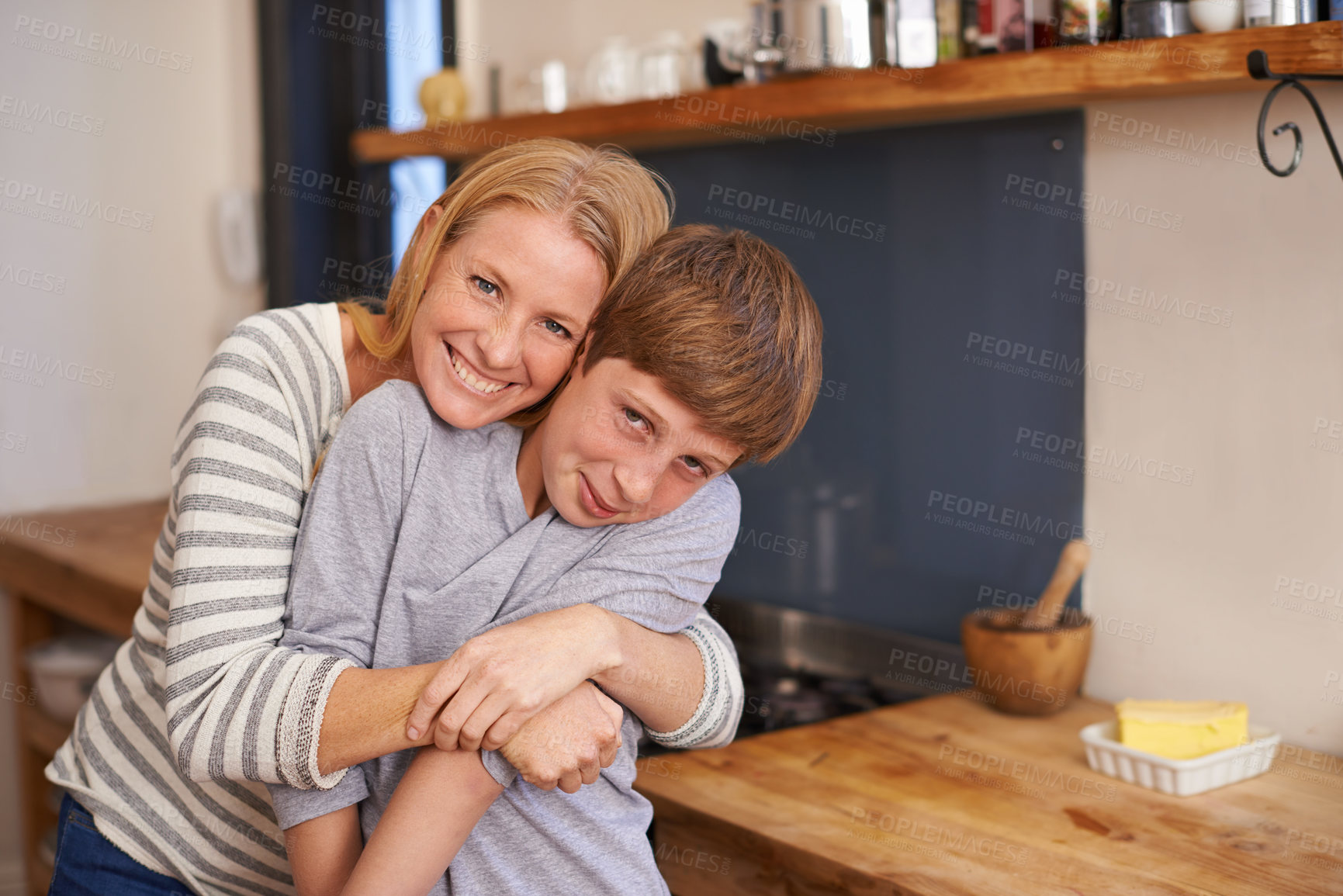 Buy stock photo A portrait of an affectionate mother and son standing in their kitchen at home