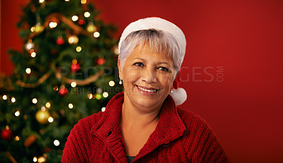 Buy stock photo Christmas, smile and face of senior woman in studio for holiday celebration by tree isolated on a red background mockup space. Xmas, mature and happy female person in hat for festive season in Brazil