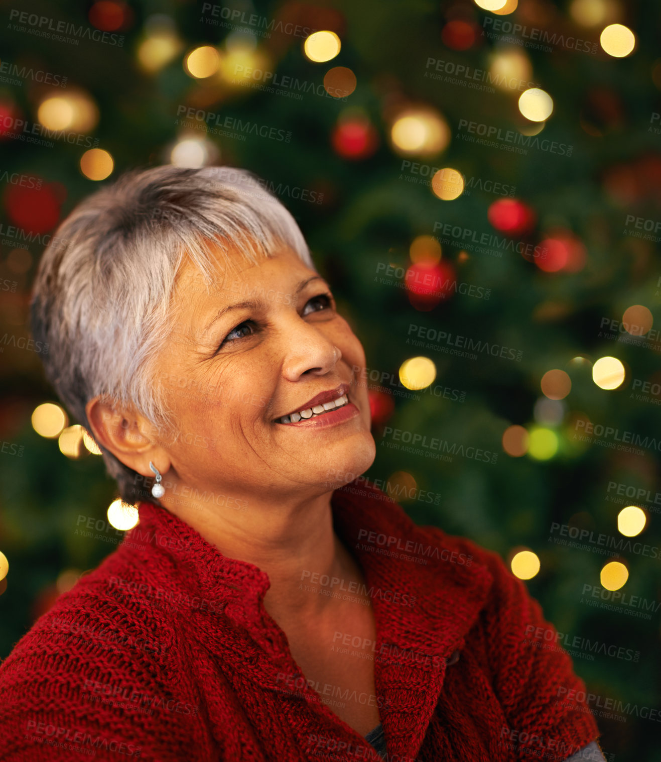 Buy stock photo Shot of a mature woman looking thoughtful in front of a Christmas tree