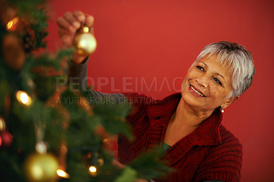 Buy stock photo Cropped shot of a mature woman decorating a christmas tree