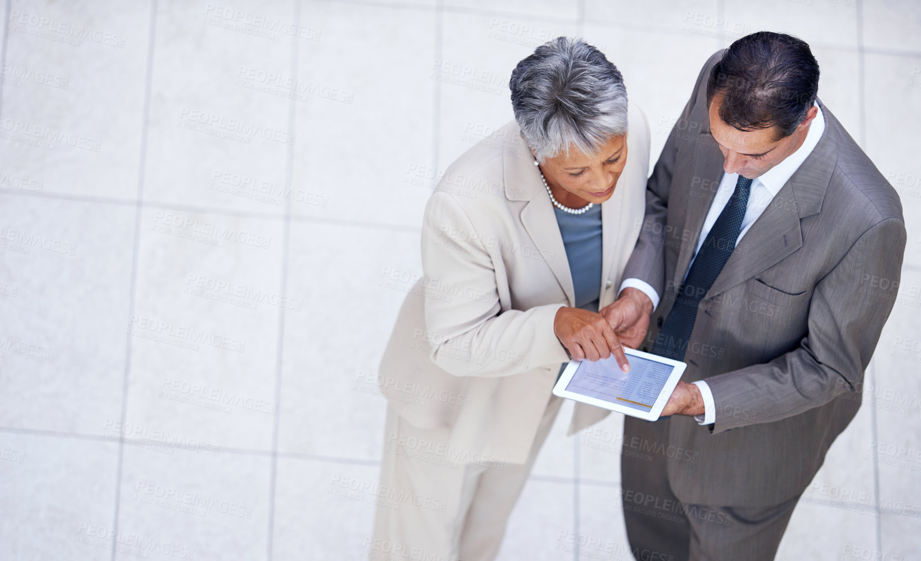 Buy stock photo High angle shot of two business colleagues standing with a digital tablet and discussing work