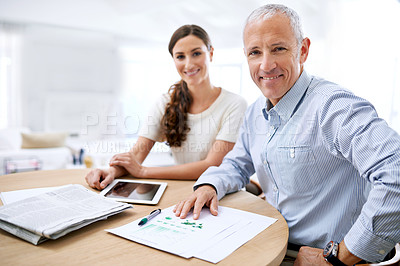 Buy stock photo Shot of two colleagues sitting at a desk together in their offiice