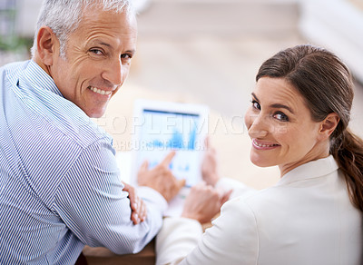 Buy stock photo Portrait of two happy colleagues using a digital tablet in the office