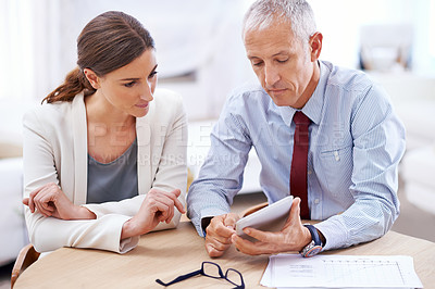 Buy stock photo Shot of two colleagues using a digital tablet in the office
