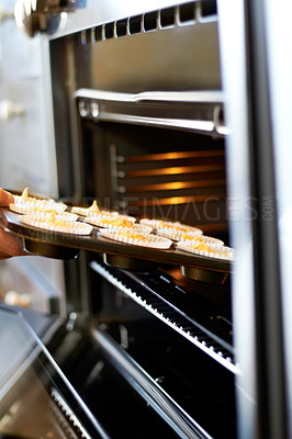 Buy stock photo Hands, closeup and tray in oven for cupcake, baking and food for small business, cafe or restaurant. Professional chef, baker or person with muffin in bakery, coffee shop or food industry startup