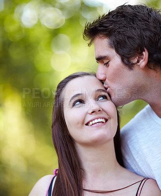 Buy stock photo Shot of young couple sharing a tender moment in the park