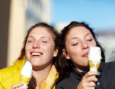 Buy stock photo Shot of two teenage sisters having ice-cream outside