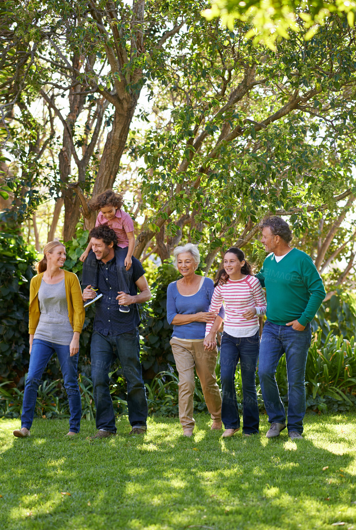 Buy stock photo Happy family, conversation and together in outdoor nature, love and bonding or relax in backyard. Generations, smile and peace or communication for support in garden or park, vacation and holiday