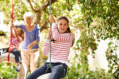 Buy stock photo Young girl, garden and grandma playing with grandkid on background or holidays, having fun on a tyre swing in summer. Excited, grandchildren and outdoors on jungle gym or on sunny portrait at a park