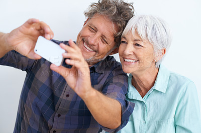 Buy stock photo Shot of a happy senior couple looking at a cellphone
