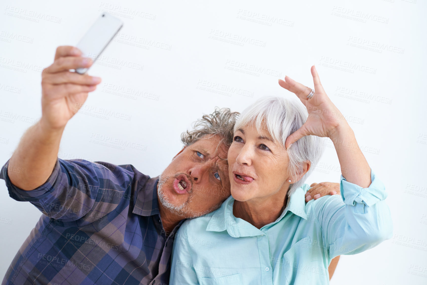 Buy stock photo Old couple, funny face in selfie and crazy together for social media post, memory and love with fun on white background. Comic, silly or goofy with people in marriage, happy in picture and mobile app