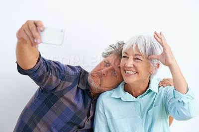 Buy stock photo Old couple, funny face in selfie and happy together for social media post, memory and love with fun on white background. Crazy, silly or goofy with people in marriage, smile in picture and mobile app