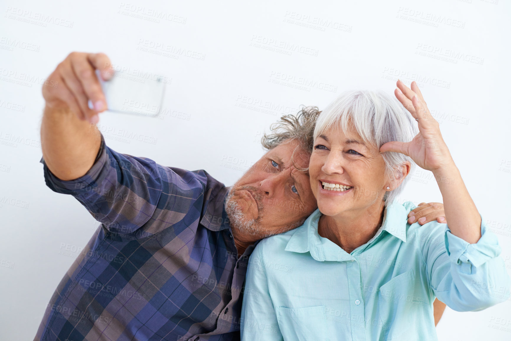 Buy stock photo Old couple, funny face in selfie and happy together for social media post, memory and love with fun on white background. Crazy, silly or goofy with people in marriage, smile in picture and mobile app