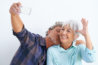 Buy stock photo Old couple, kiss in selfie and happy together for social media post, memory and love with fun on white background. Affection, trust or loyalty with people in marriage, smile in picture and mobile app