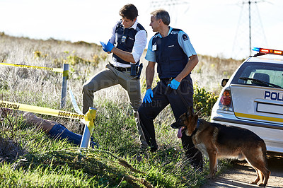 Buy stock photo Shot of two investigators taking notes while examining a crime scene