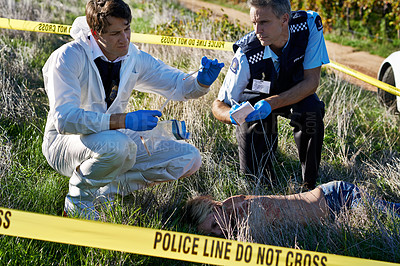 Buy stock photo Shot of two investigators examining evidence at a crime scene