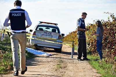 Buy stock photo Full length shot of a policeman interviewing a woman at a crimescene