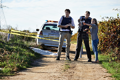 Buy stock photo Shot of a woman showing police officers where she found the body at a crimescene