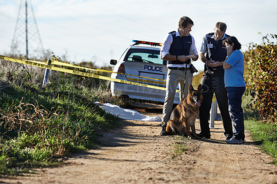 Buy stock photo Shot of two policemen interviewing a woman at a crimescene