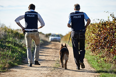 Buy stock photo Policeman, dog and walk in field for crime scene or robbery with car for search, safety and law enforcement. Detective, investigation and uniform in outdoor working at countryside with gravel road