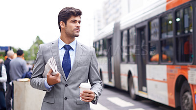 Buy stock photo A cropped shot of a handsome young man walking in the city holding coffee and a newspaper