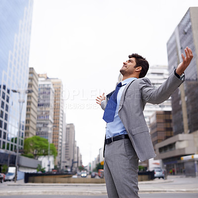 Buy stock photo A contented young businessman standing in the city with his eyes closed and his arms raised