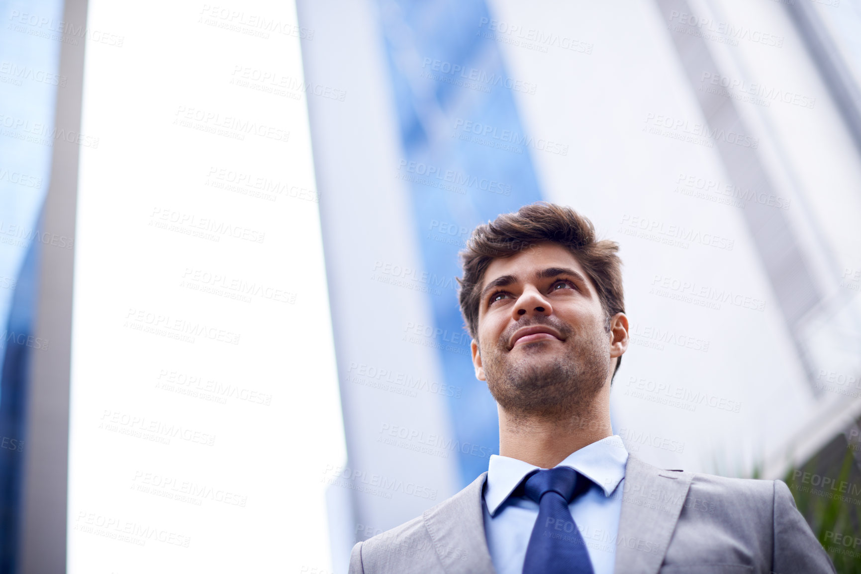 Buy stock photo a low angle shot of a handsome young businessman standing in the city