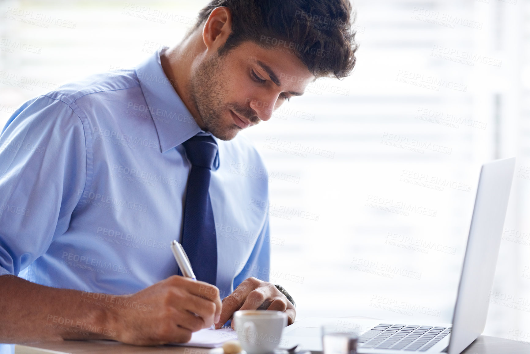 Buy stock photo A cropped shot of a handsome young businessman sitting at a coffee shop with his laptop