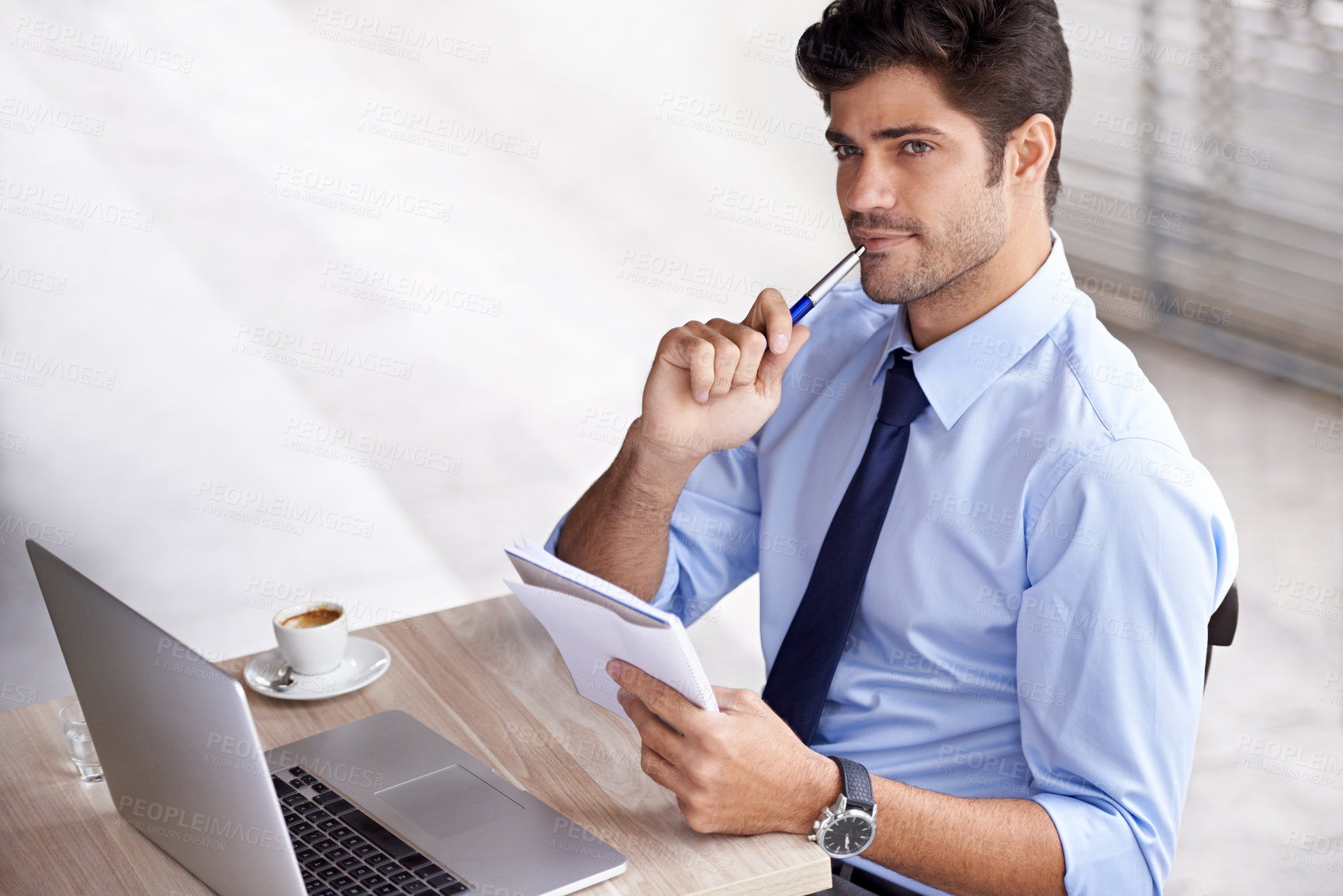 Buy stock photo A handsome young businessman sitting at a cafe with his laptop and a notepad