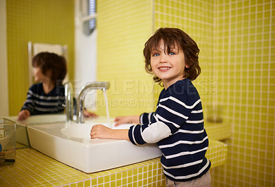 Buy stock photo A cute little boy washing his hands in the bathroom basin
