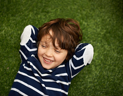 Buy stock photo Child, relax and happy on green grass for holiday, vacation and outdoor wellness in nature. High angle or above of a young kid, boy or student on lawn with excited face for playground, park or spring