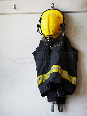 Buy stock photo Shot of a fireman's uniform hanging on the wall