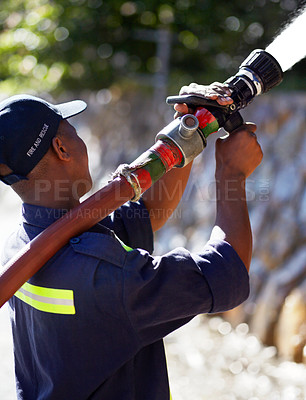 Buy stock photo Firefighter man, water and spraying hose for emergency, rescue or firefighting services in the outdoors. Fireman using big liquid pressure pipe to spray down or put out fire outside for safety