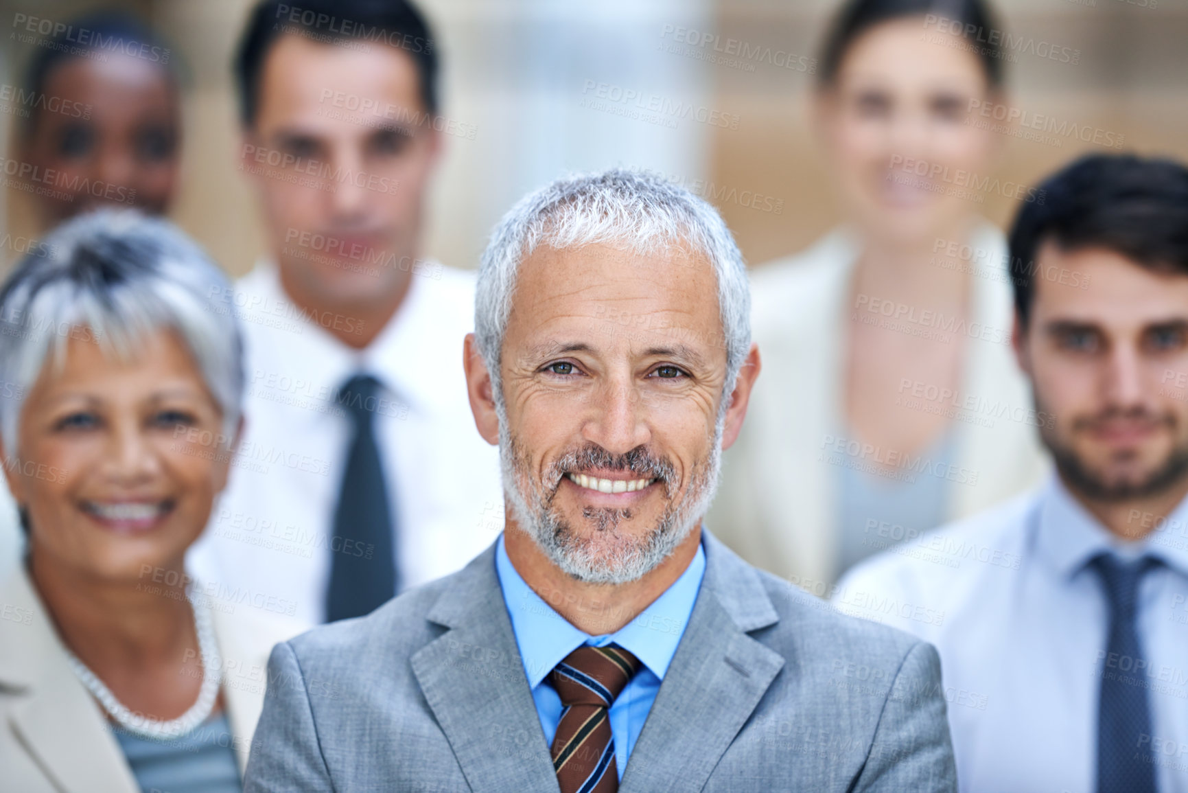 Buy stock photo Portrait of a smiling businessman surrounded by a group of his colleagues