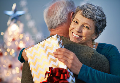 Buy stock photo Shot of a mature woman giving her partner a hug to thank him for her gift