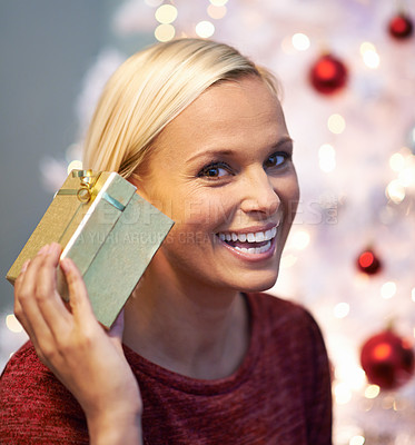 Buy stock photo Christmas, gift and excited woman listening with holiday surprise, celebration and tradition at night. Portrait of a young person by tree and bokeh lights with present, box and thanksgiving at home