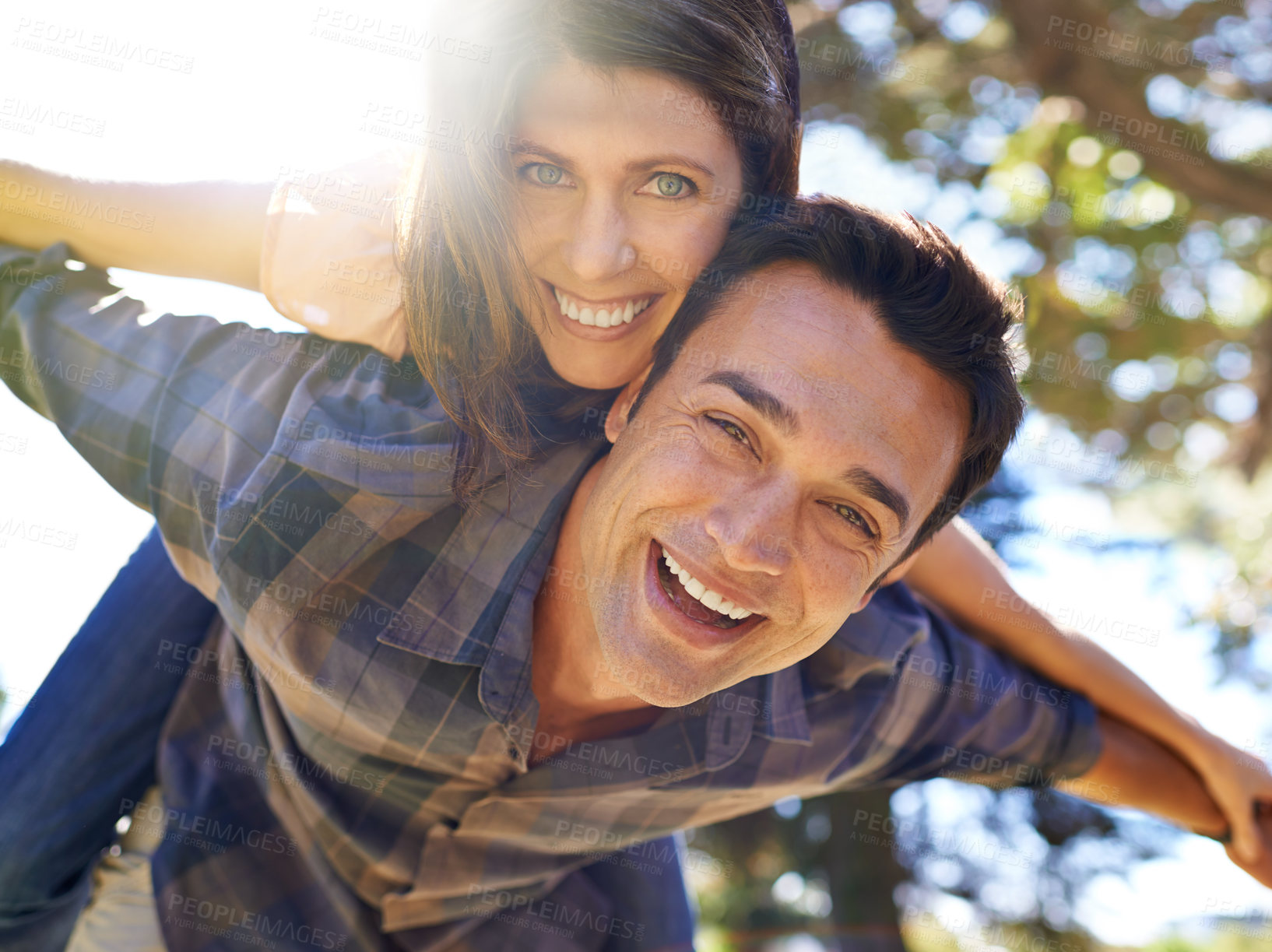 Buy stock photo Shot of a man carrying his partner on his back in the park