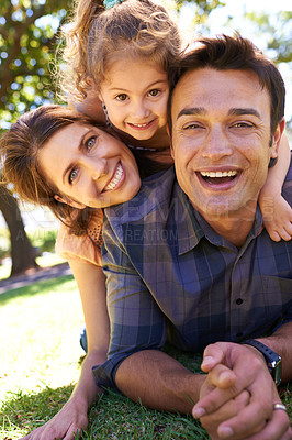 Buy stock photo Shot of a young family lying on the grass in the park