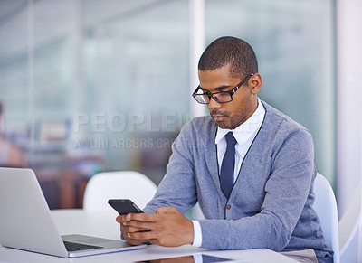 Buy stock photo Shot of a young man texting on his phone at work