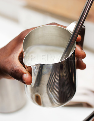 Buy stock photo Cropped shot of a barista holding a jug of hot frothed milk