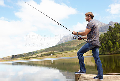 Buy stock photo Shot of a man holding a fishing rod in the outdoors