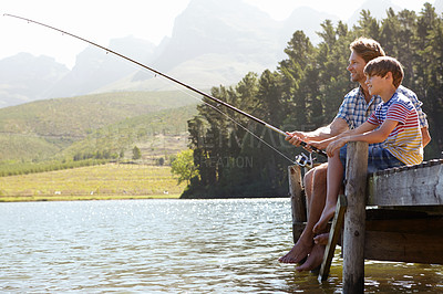 Buy stock photo Shot of a father and son sitting on a jetty fishing together
