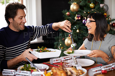 Buy stock photo Shot of a happy young couple eating Christmas dinner