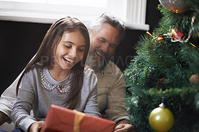 Buy stock photo Grandpa, child and gift by Christmas tree on xmas, festive season and present for bonding in lounge. Grandfather, girl and home for package on religious holiday, celebration and love for tradition